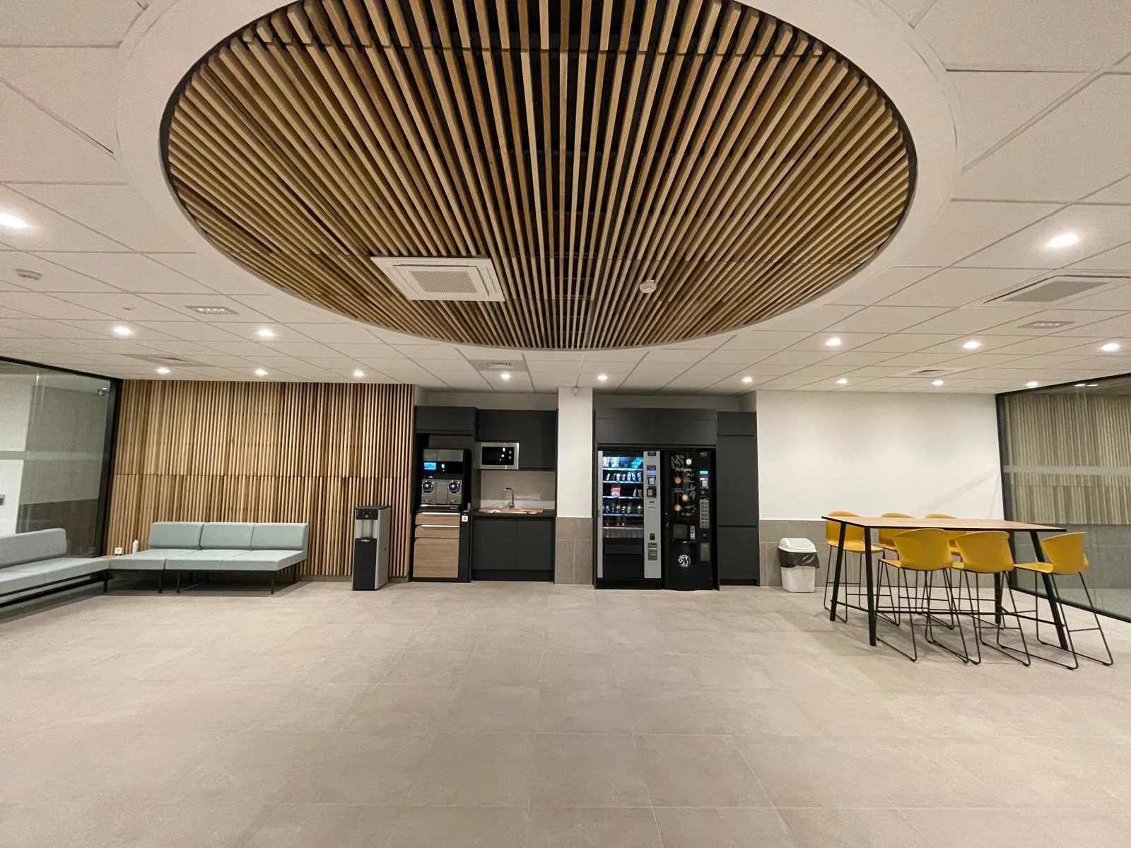 Aménagement tertiaire contemporain réalisé par EMS TRAVAUX — espace de travail avec plafond bois circulaire